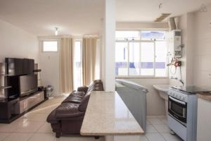 a kitchen and living room with a leather couch in a kitchen at Apartamento Lopes em Cabo Frio in Cabo Frio