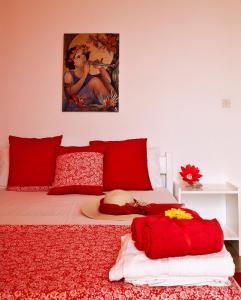 łóżko z czerwonymi poduszkami i obrazem na ścianie w obiekcie Anastasias Apartments w mieście Iria
