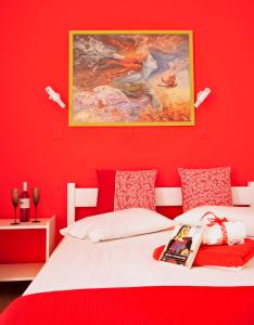 czerwona sypialnia z białym łóżkiem i obrazem w obiekcie Anastasias Apartments w mieście Iria