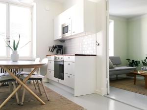 cocina con armarios blancos, mesa, mesa y sillas en Magnificent sea view! Luminous 1 br for max 4 en Helsinki