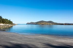 ヴァレンティア島にあるBoat House on the Beachの青い海と山々を背景にしたビーチ