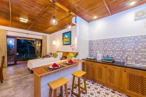 a bedroom with a bed and a kitchen with a sink at Pomelo Garden Boutique Villa in Hoi An