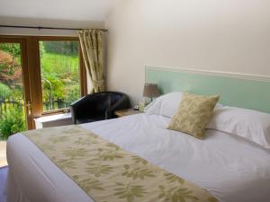 a bedroom with a bed and a chair and a window at Ghyll Farm B & B in Lamplugh