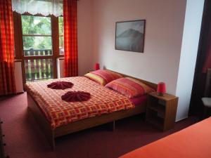 Un dormitorio con una cama con almohadas rojas y una ventana en Pension Borůvka, en Špindlerův Mlýn