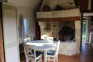 a dining room with a table and a fireplace at La Bouillerie du Clos in Branville