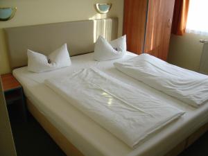 ein weißes Bett mit weißer Bettwäsche und Kissen darauf in der Unterkunft REGIOHOTEL Halle Leipzig Airport in Schkeuditz