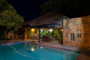 a swimming pool in front of a house at night at Bayswater Lodge in Bloemfontein