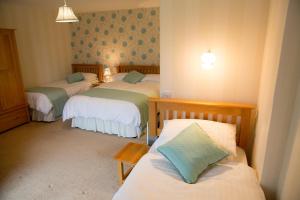 Habitación con 3 camas en una habitación en Weir Mill Farm en Cullompton