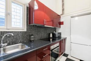 a kitchen with red cabinets and a sink at Trendy Minimal Flat in posh Athens in Athens +6 photos