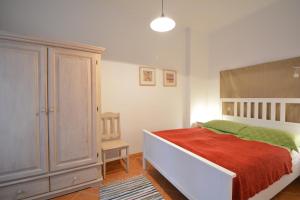 um quarto com uma cama branca e um cobertor vermelho em Apartamenty Rybak 3 em Niechorze