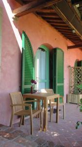 un patio con tavolo e sedie e persiane verdi di Villa il Pino by VacaVilla a Lari