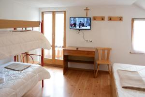 a bedroom with a desk and a tv on a wall at Casa Teresa Martin in San Vigilio Di Marebbe