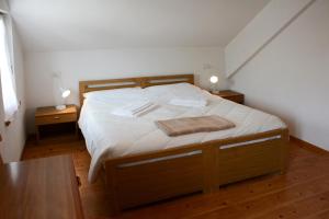 a bedroom with a bed with white sheets and two tables at Casa Teresa Martin in San Vigilio Di Marebbe