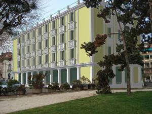 ヴィチェンツァにあるホテル カンポ マルツィオの目の前に木々が植えられた大きな黄色と白の建物