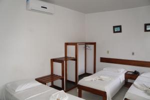 two beds in a room with white sheets at Pousada Do Bosque in Itajuípe