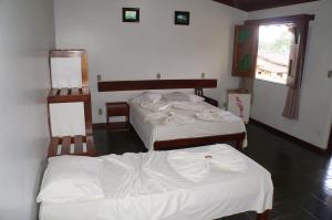 a room with two beds with white sheets at Pousada Do Bosque in Itajuípe