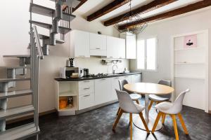 cocina con armarios blancos, mesa y sillas en Lima Apartments en Milán