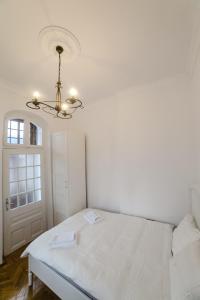 Habitación blanca con cama y lámpara de araña. en Castelul Cantacuzino en Buşteni