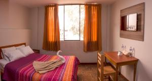 1 dormitorio con cama, mesa y ventana en Hotel Olímpica, en Arequipa