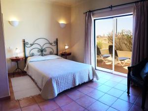 1 dormitorio con 1 cama y balcón con patio en Vila Castelo Tradicional, en Ferragudo