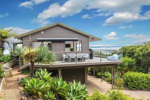 une maison avec une terrasse munie de tables et de chaises. dans l'établissement Sunset Sanctuary- Waiheke Escapes, à Omiha