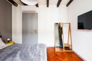 1 dormitorio con 1 cama, TV y espejo en Lima Apartments en Milán