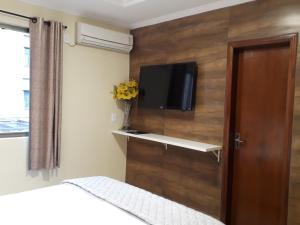 a bedroom with a tv on a wall with a bed at Hotel Loureiro in Rio Branco