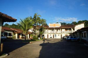 a building with palm trees in front of a parking lot at Pousada Do Bosque in Itajuípe