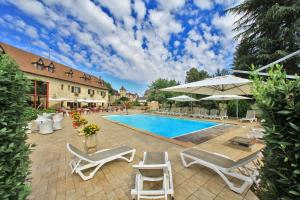 a pool with chairs and umbrellas next to a building at Logis Auberge La Diege in Capdenac-Gare