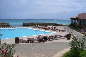 una piscina con gente sentada en bancos junto al océano en Porto Antigo Three Bed Apartment with Sea View, en Santa Maria