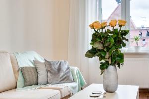 グダニスクにあるElite Apartments Korzenna City Centerのリビングルーム(テーブルに黄色のバラが飾られた花瓶付)
