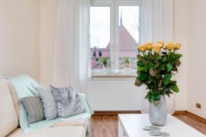 a living room with a couch and a vase with yellow roses at Elite Apartments Korzenna City Center in Gdańsk