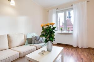 a living room with a white couch and a vase with yellow roses at Elite Apartments Korzenna City Center in Gdańsk