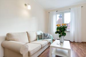 a living room with a white couch and a vase of flowers at Elite Apartments Korzenna City Center in Gdańsk