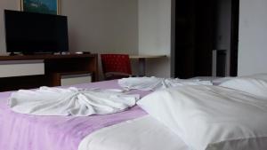 a bedroom with a bed with white sheets and a desk at Hotel Monte Líbano in Laguna