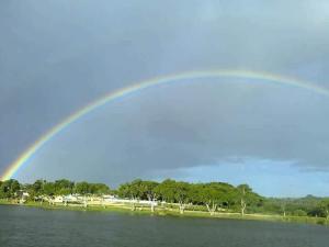 a rainbow in the sky over a body of water at Pousada Do Bosque in Itajuípe