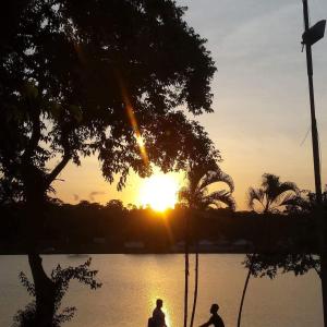two people standing in front of a lake at sunset at Pousada Do Bosque in Itajuípe