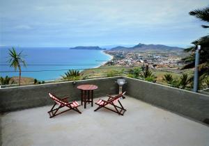 two chairs and a table on a balcony overlooking the ocean at Porto Santo Balcony View House in Porto Santo +8 photos