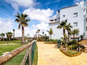 a white building with palm trees in front of it at Laduana LaCarmen & LaPepa in Rota