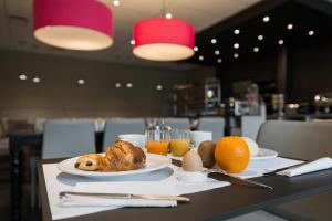 einen Tisch mit einem Frühstück mit Croissants, Eiern und Orangen in der Unterkunft Hotel Expo in Brüssel