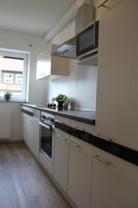 a large kitchen with white cabinets and a window at Ferienwohnung I in Schnelldorf