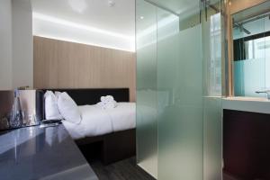 una camera d'albergo con letto e doccia in vetro di The Z Hotel Victoria a Londra