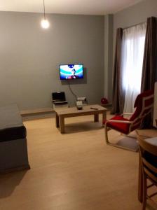 ein Wohnzimmer mit einem TV und einem Tisch in der Unterkunft Renovated apartment in Athen