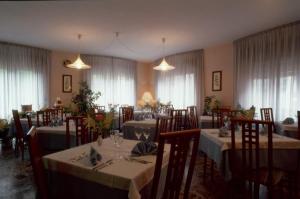 uma sala de jantar com mesas, cadeiras e janelas em Albergo Miramonti em Arta Terme