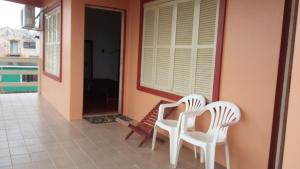 two white chairs sitting on the porch of a house at Pousada M&J in São Gabriel