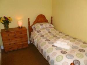 a bedroom with a bed and a dresser with a lamp at Nether Onston Cottage in Stenness