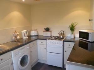 uma cozinha com uma máquina de lavar roupa, um lavatório e um fogão em Nether Onston Cottage em Stenness