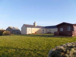 a house in a yard with a grass field at Nether Onston Cottage in Stenness