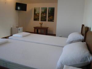 two beds in a room with white sheets at Casa Hora in Suceava