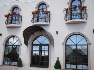 a white building with windows and balconies with flowers at Casa Hora in Suceava +5 photos